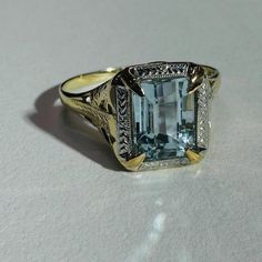 The aqua is approximately 1.1 carat with a beautiful medium blue hue, and a shimmering emerald cut. The ring measures 12mm wide with a rise of 6mm, and the shank is 1mm Marked 10K OB Very good condition Aquamarine Diamond Cut Rings Fine Jewelry, Aquamarine Diamond Cut Rings In Fine Jewelry Style, Yellow Gold Octagon Topaz Ring For Anniversary, Classic Aquamarine Diamond Cut Ring, Classic Aquamarine Rings With Diamond Cut, Classic Aquamarine Ring With Diamond Cut, Classic Aquamarine Baguette Cut Jewelry, Classic White Gold Aquamarine Rings, Classic Aquamarine Rings With Accent Stones