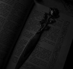 an open book with a rose on it and a knife sticking out of the pages