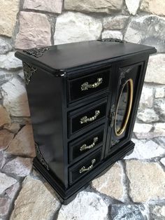 a black and gold jewelry box sitting on top of a stone floor next to a brick wall