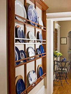 a wooden shelf filled with blue and white plates on top of a hard wood floor