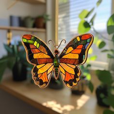 a stained glass butterfly ornament hanging from a string on a window sill