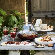 a table topped with plates and bowls filled with food next to wine glasses on top of a wooden table