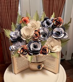 an open book sitting on top of a table with paper flowers in the middle of it