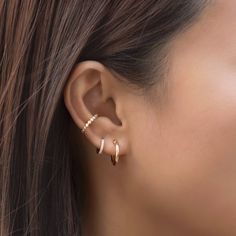 a woman's ear is shown with two small gold hoops on the side