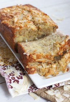 two slices of banana bread on a white plate with floral napkins next to it