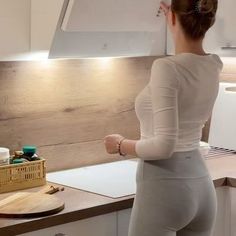 a woman is standing in the kitchen with her back to the camera and looking at something on the counter