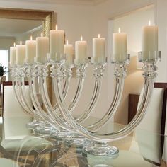 a glass table topped with lots of white candles