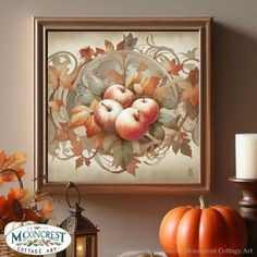 an apple painting hangs on the wall next to candles and pumpkins in front of it