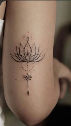 a woman's leg with a lotus tattoo on the back of her thigh and an arrow