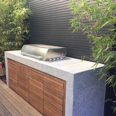 a bbq grill sitting on top of a wooden table next to a planter