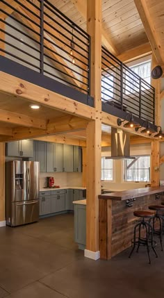 an open kitchen and living room area with wood beams on the ceiling, stainless steel appliances and counter tops