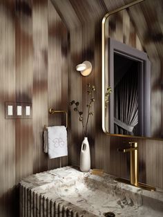 a bathroom with marble counter top and gold accents on the wall, along with a large mirror