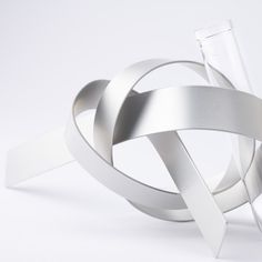 an abstract silver object is shown on a white background, with one piece cut out and the other part folded up