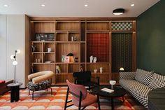 a living room filled with lots of furniture next to a wall mounted bookshelf