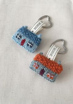 two crocheted key fobs are sitting on a white tablecloth, one is blue and the other is orange