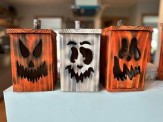 three wooden boxes with faces painted on them are sitting on a table in a room