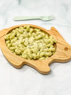 a wooden bowl filled with macaroni and cheese on top of a white counter