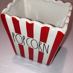 a red and white striped popcorn bucket with the word popcorn written on it's side