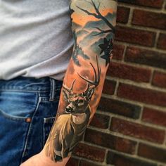 a man with a deer tattoo on his arm next to a brick wall and tree