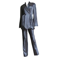 A beautiful black silk pant suit from Yumi Eto. The double breasted shawl collar jacket is gorgeous with matching fine inner adjustable straps which can be moved to different configuration with buttons inside of the jacket to change the hemline shape and length. The pants have straight legs and a back zipper. The jacket has grey mother of pearl buttons in front, all inside seams are beautifully bound finished and both pieces are unlined. Fits sizes Small, Medium. Marked US size 8. Jacket Bust 34 Chic Silk Suits For Formal Occasions, Luxury Evening Pantsuit With Notch Lapel, Chic Silk Suits With Notch Lapel, Chic Silk Suit With Notch Lapel, Chic Silk Notch Lapel Suits, Chic Tailored Silk Suits, Luxury Tailored Evening Pantsuit, Satin Suits With Long Sleeves For Evening, Chic Satin Suits For Evening