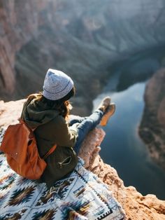 a woman sitting on top of a mountain next to a lake with a quote above her