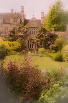 a large house surrounded by lush green trees and flowers