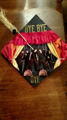 a graduation cap with the words bye bye on it and some decorations hanging from it