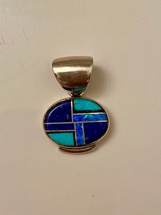 This beautifully well crafted Oval Pendant has been handmade by a Navajo Artisan. The Colors of the Pendant come from Lapis Lazuli, Turquoise and Blue Opal. The Pendant measures 1” long and 1” wide. It is stamped Sterling and signed by the Artist. “Winds of Wisdom” (Lapis Lazuli, Turquoise and Blue Opal. The Navajo (Dine’) believe that the wind is a powerful source. The native tradition believes that at any moment, the blowing wind can inspire one with hope, resolve, and great wisdom. Wisdom has Oval Pendant, Blue Opal, Turquoise Blue, Lapis Lazuli, Opal, Stamp, Turquoise, Pendant, Blue