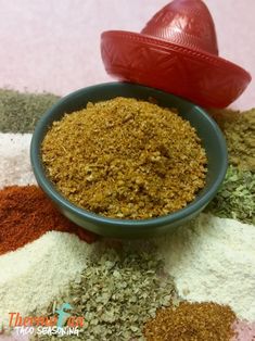 a bowl filled with spices sitting on top of a table next to a red pepper shaker