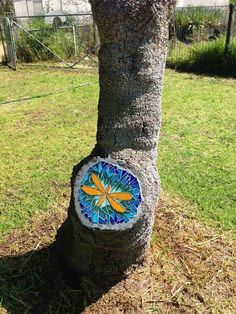 a tree trunk with a colorful glass decoration on it