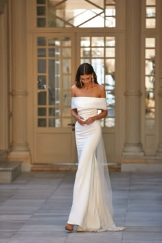 a woman in a white wedding dress looking down at her phone