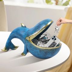 a person is holding a cell phone in a bowl shaped like a dolphin