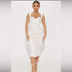 a woman wearing a white bandaged dress and high heeled sandals standing in front of a white background