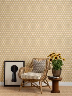 a chair and vase with flowers in front of a wallpapered background that has an abstract pattern