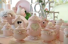 there are many pink teapots and cups on the table with white doily