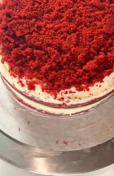 a red velvet cake with white frosting and sprinkled crumbs on top