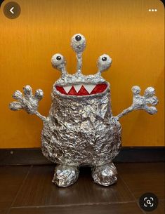 a tin foil monster sitting on top of a wooden floor