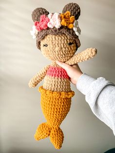 a crocheted doll is held up in the air by someone's hand