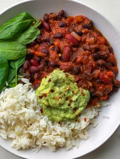 a white plate topped with rice, beans and guacamole next to a fork