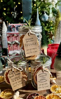 jars filled with dried oranges and spices on top of a wooden table next to christmas trees