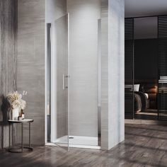 a walk in shower sitting on top of a wooden floor next to a white table