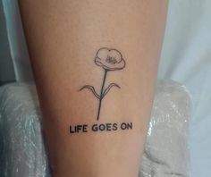 a small tattoo with the words life goes on and a single flower in black ink