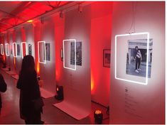 people are looking at pictures on display in a red light room that is lit up