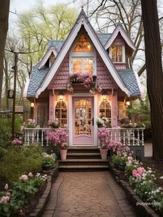 a pink and white house with flowers in the front yard, stairs leading up to it