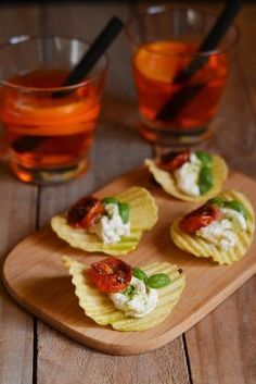 small crackers with tomatoes and basil on them next to two glasses of orange juice