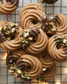 chocolate covered donuts with nuts on a cooling rack in front of other donuts