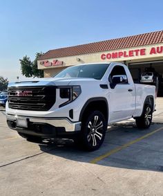 a white truck is parked in front of a dealership with the words complete auto written on it