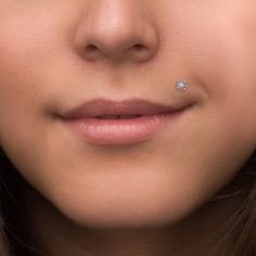 a close up of a woman with a nose ring on her nose and an ear piercing in front of her face