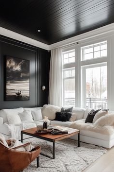 a living room filled with white furniture and black painted walls, along with large windows