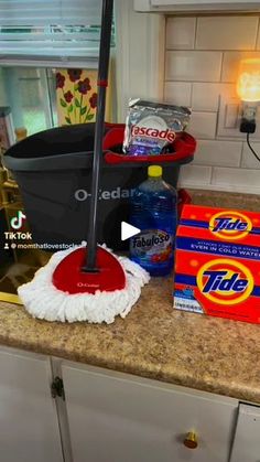 a mop sitting on top of a kitchen counter next to boxes and cleaning supplies